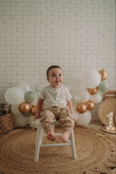 a baby is sitting on a chair in front of balloons and garlands for a photo shoot