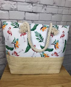 a white bag with flamingos and palm leaves on it sitting on top of a wooden table