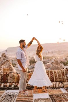 a man and woman standing on top of a rug holding hands