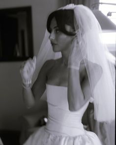 a woman in a wedding dress is talking on her cell phone while wearing a veil