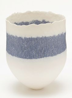 a white and blue striped vase sitting on top of a table