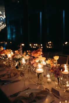 a long table is set with candles and flowers in glass vases on the tables