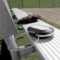 an electronic device sitting on top of a wooden bench next to a bag and glove