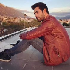 a man in a red jacket is sitting on the roof