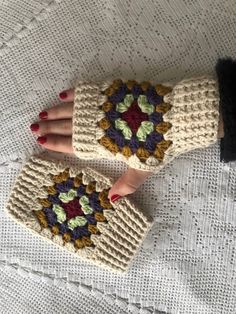 two hands wearing knitted mittens with flowers on them