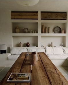 a wooden table sitting in the middle of a living room next to a white couch