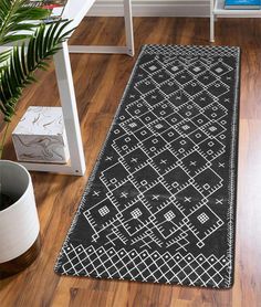 a black and white rug on the floor in front of a table with potted plants