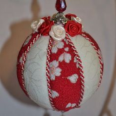 a red and white ornament with flowers on it's side hanging from a hook