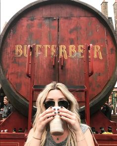 a woman drinking from a coffee cup in front of a barrel with the word butterer written on it