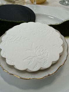 two white plates sitting on top of a table next to black and gold place mats