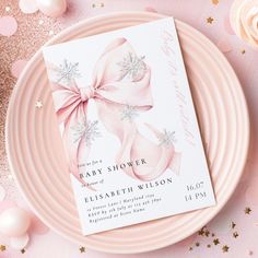 a pink and white baby shower card on a plate