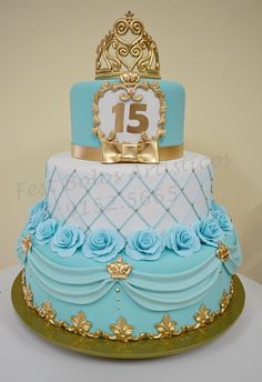 a blue and white tiered cake with gold trimmings is displayed on a table