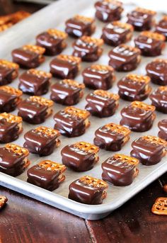 chocolate covered pretzels sitting on top of a cookie sheet