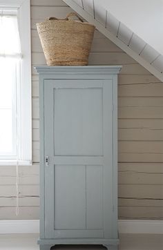 a blue cabinet with a basket on top of it in front of a white wall