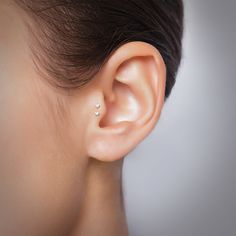 a woman's ear is shown with a single diamond in the middle of it