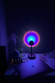 a laptop computer sitting on top of a desk next to a lamp in the dark