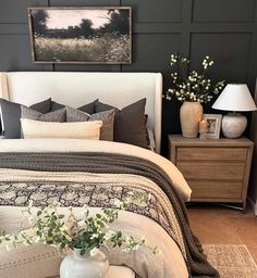 a white bed sitting in a bedroom next to a night stand with flowers on it