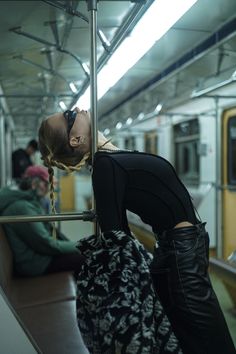 a woman in black boots leaning against a rail with her head down on the ground