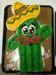 a cake in the shape of a cactus with a mustache and sombrero on top