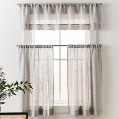 a window with two curtains and a potted plant