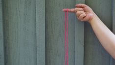 a hand reaching up to the side of a wall with a string attached to it