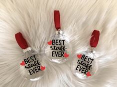 three glass ornaments with the words best shark ever on them, hanging from a white fur background