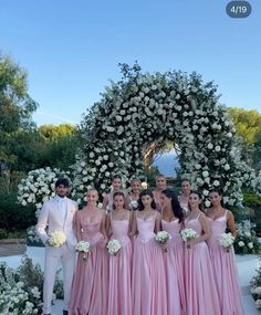 a group of people standing next to each other in front of a flower covered arch