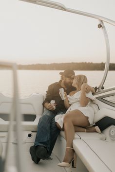 a man and woman sitting on the back of a boat drinking beer while looking at each other