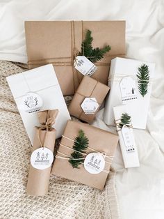 wrapped presents are tied with twine and decorated with evergreen branches, pine cones and white tags