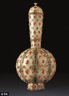 an ornate white vase with red, yellow and green designs on it's sides