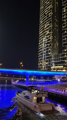 a boat is traveling down the river in front of some tall buildings at night time