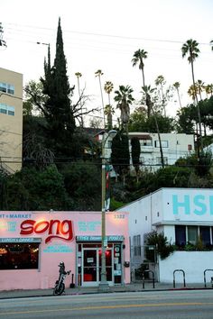 a pink building with neon lights and palm trees in the background