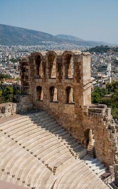 the ruins of an ancient amphit in front of a cityscape with mountains in the background