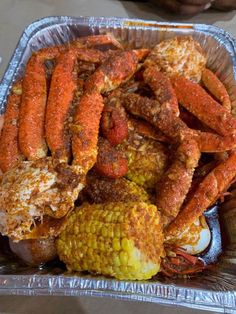 there is a container full of crab legs and corn on the cob