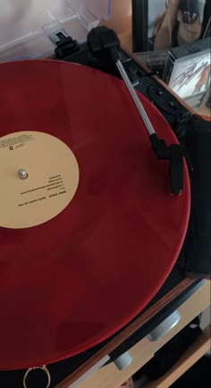 a red record player sitting on top of a wooden table