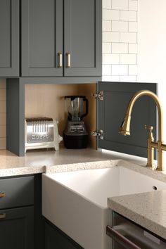 a kitchen with gray cabinets and gold faucet