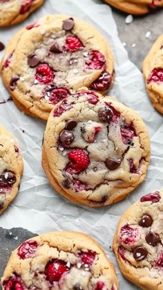 chocolate chip cookies with raspberries and white chocolate chips on parchment paper lined up