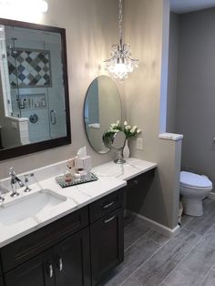 a bathroom with two sinks, a toilet and a large mirror above the vanity area