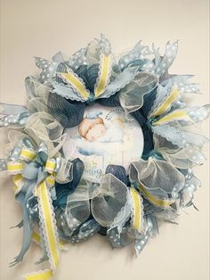 a wreath with a baby's photo on it and yellow ribbons around the edges