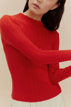 woman in red sweater High Neck Knit Sweater With Ribbed Neckline, High Neck Sweater With Ribbed Cuffs For Layering, Knit Sweater With Ribbed High Neckline, Ribbed Turtleneck Knit Sweater, Snug Textured Knit Long Sleeve Top, Layering Turtleneck Sweater With Ribbed Neckline, Turtleneck Sweater With Ribbed Neckline For Layering, Snug Winter Tops With Ribbed Cuffs, Snug Winter Top With Ribbed Cuffs