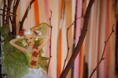 a fairy figurine hanging from a tree branch in front of a striped wall