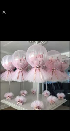 some pink balloons are hanging from the ceiling in front of a table with tulle and bows