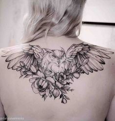 the back of a woman's shoulder with an owl and flowers tattoo