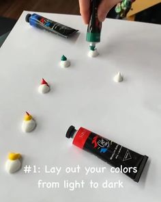 someone is painting small white and green objects on a sheet of paper with black marker