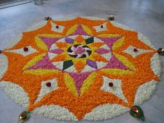 an orange and white flower design on the ground with bells around it, surrounded by flowers