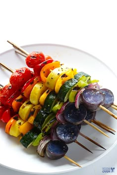 several skewers of colorful vegetables on a white plate