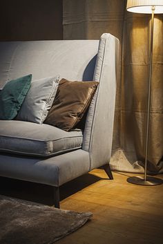 a couch with many pillows on it next to a lamp