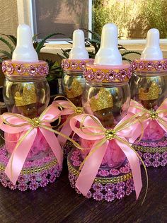 three baby bottles with pink and gold bows on them