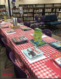 the table is covered with red and white checkered cloths, bookshelves are in the background