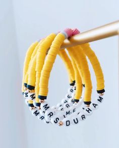 three bracelets are hanging from a metal pole with letters on them and beads in the middle